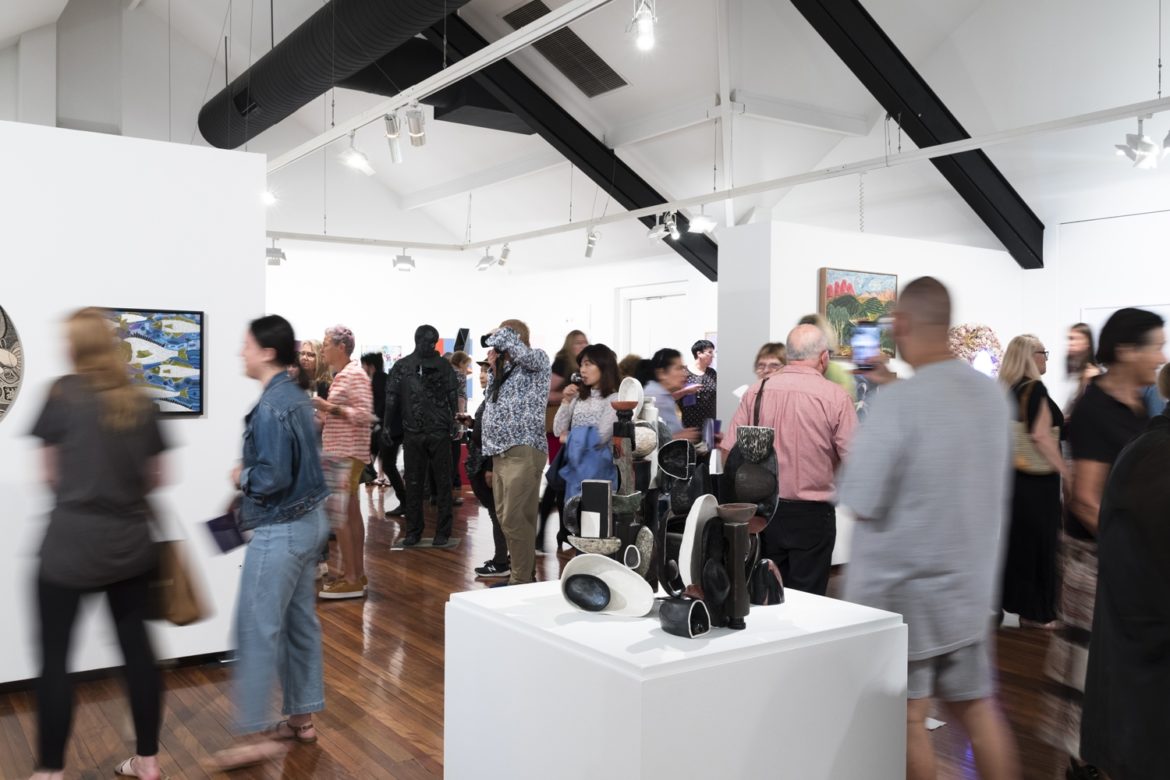 A crowd of people moving through a gallery space during an exhibition