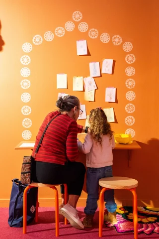 Enjoy a fun time of play and creativity in the Makers Space with Monica Rani Rudhar!  The colourful walls are full of large scale and soft jewellery artworks that invite a sense of joy and curiosity, inspired by her Indian and Romanian heritage. 
Touch them, move them, try them on, then chill out with some hands-on making activities  Until 13 December.  Learn more via our website! 
More info via link in bio.  @blacktowncitycouncil @monicaranirudhar  #BlacktownArts #BlacktownCityCouncil #SchoolHolidays #Workshops #Kids  ---
Images: 1 and 2, Family Day inspired by A Real Experience, photo by Tammy Dang, Makers Space with Monica Rani Rudhar, Photo by Garry Trinh.  ID: Image 1, a caregiver with young child sitting at a table with backs to the camera in a bright orange room drawing. Image 2, shows a group of adults and children creating designs at a table with colourful  pipe cleaners. Image 3, showcases a bright orange room with a table and chairs in front of 3 artworks of oversized earring sculptures.